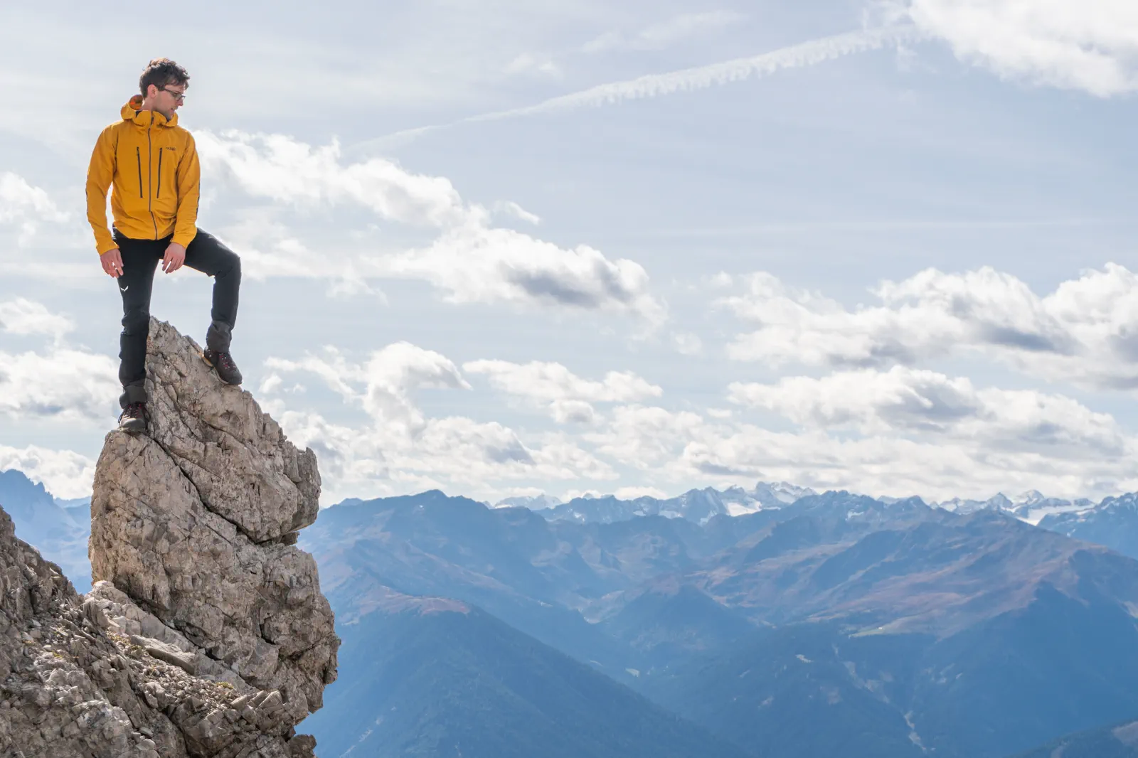 Lukas stands on an exposed rock high above a wide alpine valley.
